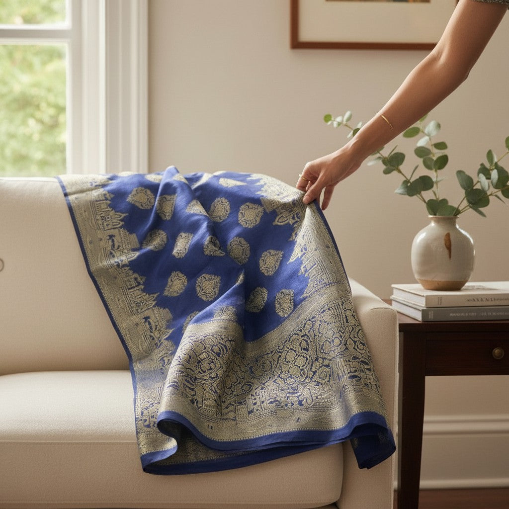 Blue and gold-colored patterned wrap draped over a white armchair, showing its broad decorative border.